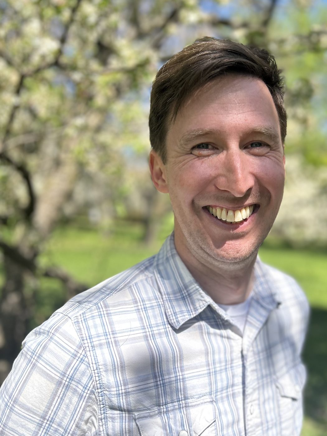 Thomas smiling under blossoming trees